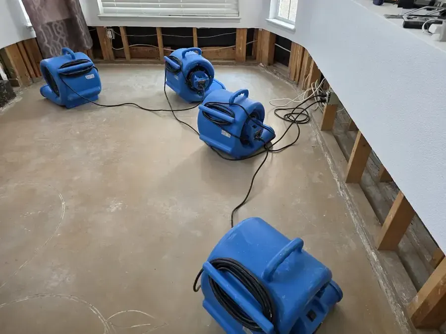 Air movers lined up along a flood cut in an Aurora room during structural drying